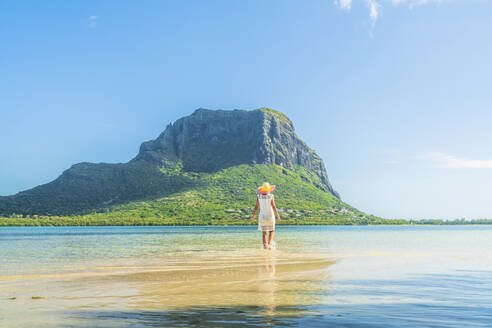 Frau bewundert den Berg Le Morne im seichten Wasser der türkisfarbenen Lagune, La Gaulette, Mauritius, Indischer Ozean, Afrika - RHPLF14204
