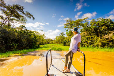 Woman searching for wildlife on a boat tour of the Amazon River, Peru, South America - RHPLF14215