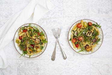 Zwei Teller vegetarischer Nudelsalat mit gegrillten Zucchini, Tomaten, Rucola, roten Zwiebeln und Balsamico-Essig - LVF08668