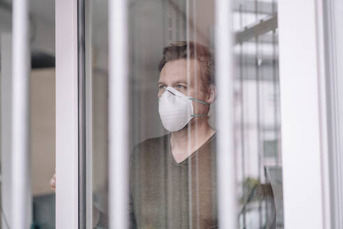 Porträt eines Mannes mit Schutzmaske hinten am Fenster - JOSEF00107