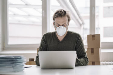 Businessman wearing protective mask and using laptop - JOSEF00112