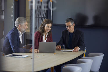 Two businessmen and businesswoman working together on a project in office - RBF07141