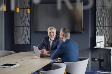 Zwei lächelnde Geschäftsleute arbeiten gemeinsam an einem Projekt im Büro - RBF07144