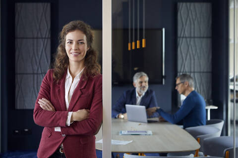 Porträt einer selbstbewussten Geschäftsfrau im Büro mit Kollegen im Hintergrund, lizenzfreies Stockfoto