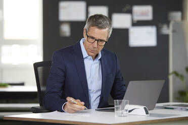 Businessman working at desk in office - RBF07156