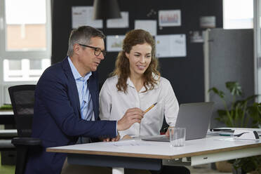 Businessman and businesswoman working together on laptop in office - RBF07171