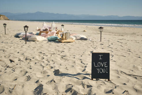 I LOVE YOU Schild auf Plakat in der Nähe von Esstisch am Strand gegen klaren blauen Himmel während sonnigen Tag, Nayarit, Mexiko - ABAF02281