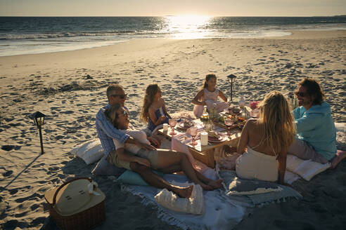 Familie und Freunde genießen ein Picknick am Strand während des Sonnenuntergangs, Riviera Nayarit, Mexiko - ABAF02291