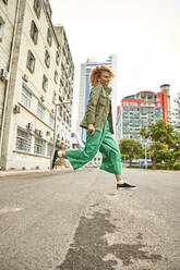 Young woman jumping on a street - VEGF01805