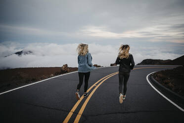 Rückansicht von Freunden, die gemeinsam auf der Straße am Vulkan Haleakala laufen, Hawaii, Maui, USA - LHPF01196