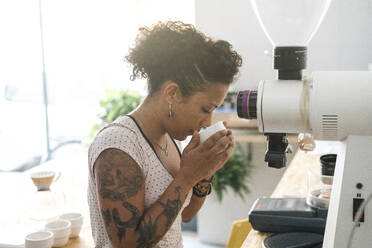 Frau arbeitet in einer Kaffeerösterei und riecht am Produkt - JPIF00525