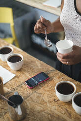 Close-up of woman working in a coffee roastery preparing coffee - JPIF00533