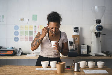 Woman working in a coffee roastery tasting product - JPIF00536