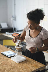 Woman working in a coffee roastery preparing fresh filtered coffee - JPIF00539