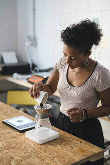 Frau arbeitet in einer Kaffeerösterei und bereitet frischen Filterkaffee zu - JPIF00539