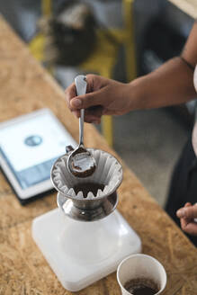 Nahaufnahme einer Frau, die in einer Kaffeerösterei frischen Filterkaffee zubereitet - JPIF00540