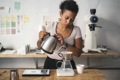 Frau arbeitet in einer Kaffeerösterei und bereitet frischen Filterkaffee zu - JPIF00541