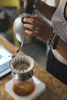 Frau arbeitet in einer Kaffeerösterei und bereitet frischen Filterkaffee zu - JPIF00542