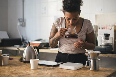 Frau arbeitet in einer Kaffeerösterei und riecht an Kaffee - JPIF00543