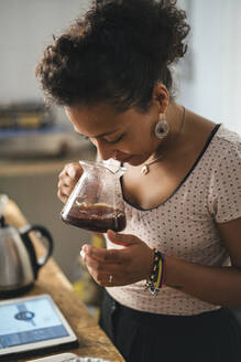 Frau arbeitet in einer Kaffeerösterei und riecht an Kaffee - JPIF00544