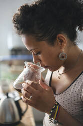 Frau arbeitet in einer Kaffeerösterei und riecht an Kaffee - JPIF00545