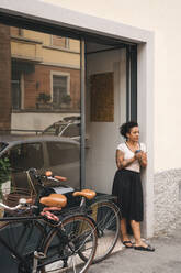Woman having a coffee break in front of her store - JPIF00553