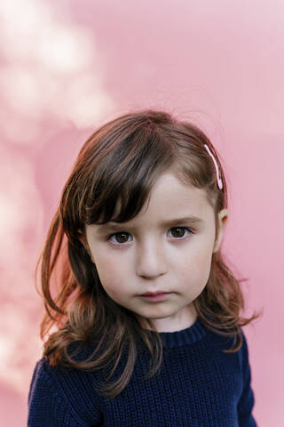 Porträt eines traurigen kleinen Mädchens vor einem rosa Hintergrund, lizenzfreies Stockfoto