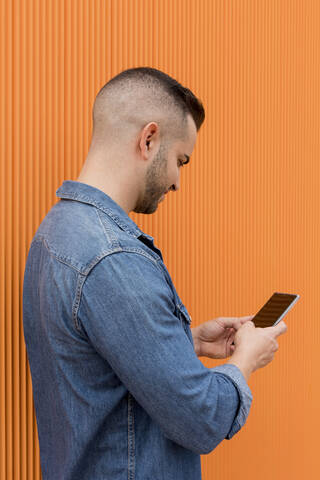 Porträt eines jungen, coolen Mannes auf orangefarbenem Hintergrund., lizenzfreies Stockfoto