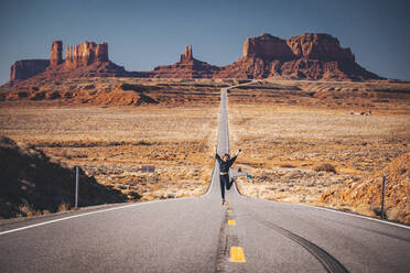 Girl is jumping on the road near Forrest Gump Point, Monument Valley - CAVF77230