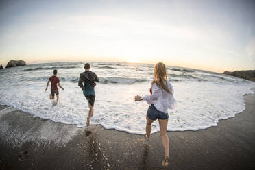 Group of teenagers having fun on beach at sunset - CAVF77246