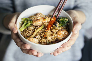 Female holding a bowl of seafood thai noodles - CAVF77279