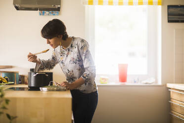 Junge Frau beim Kochen zu Hause in einer Küche - CAVF77385