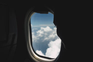 Nahaufnahme von Person Blick auf Wolken durch Flugzeugfenster - EYF01300