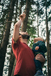 Low Angle View Of Father Carrying Son While Standing In Forest - EYF01492