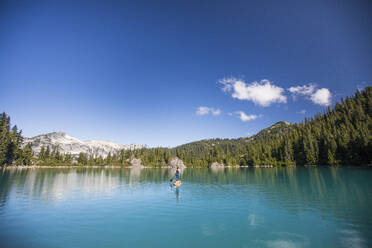 Fit woman paddles Stand up paddle board on blue lake. - CAVF77435