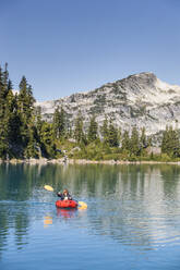 Retired woman paddling on remote mountain lake. - CAVF77450