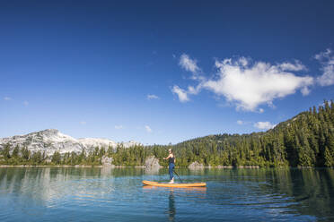 Healthy fit woman using stand up paddle board on lake. - CAVF77455