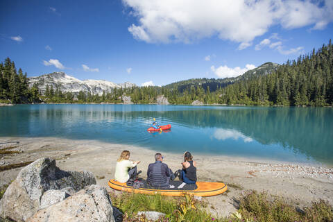 Familie entspannt sich gemeinsam an einem abgelegenen See, Bruder paddelt auf dem See., lizenzfreies Stockfoto