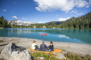 Familie entspannt sich gemeinsam an einem abgelegenen See, Bruder paddelt auf dem See. - CAVF77472