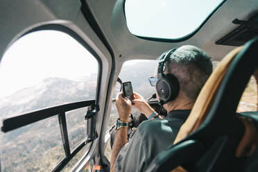 Rentner fotografiert mit Telefon aus dem Hubschrauber heraus. - CAVF77481