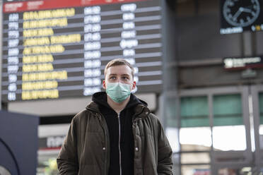 Young man with face mask at train station in the city - VPIF02126