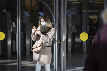 Woman with face mask, using smartphone at subway station - VPIF02135