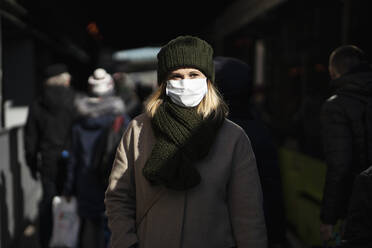 Woman with face mask standing at bus stop - VPIF02138