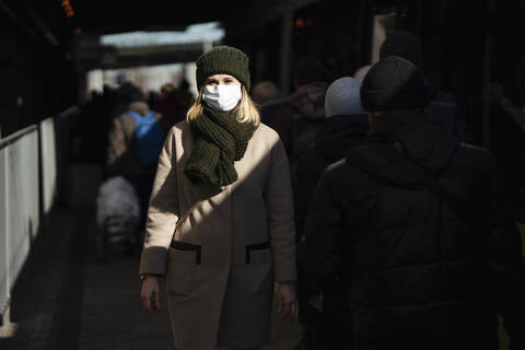 Frau mit Gesichtsmaske an der Bushaltestelle, lizenzfreies Stockfoto