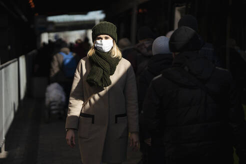 Woman with face mask standing at bus stop - VPIF02139