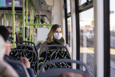 Frau mit Gesichtsmaske in Straßenbahn sitzend - VPIF02141