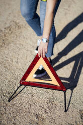 Close-up of woman posting warning triangle - OCMF01074