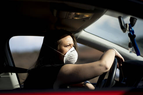 Woman in car wearing respirator mask - OCMF01080