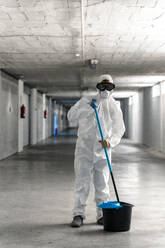 Woman wearing protective clothing wiping floor of car park - DLTSF00648
