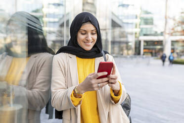 Portrait of smiling young woman using smartphone in the city - WPEF02724